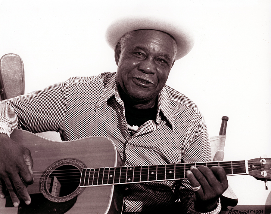 Older Alfred "Snuff" Johnson, playing his guitar